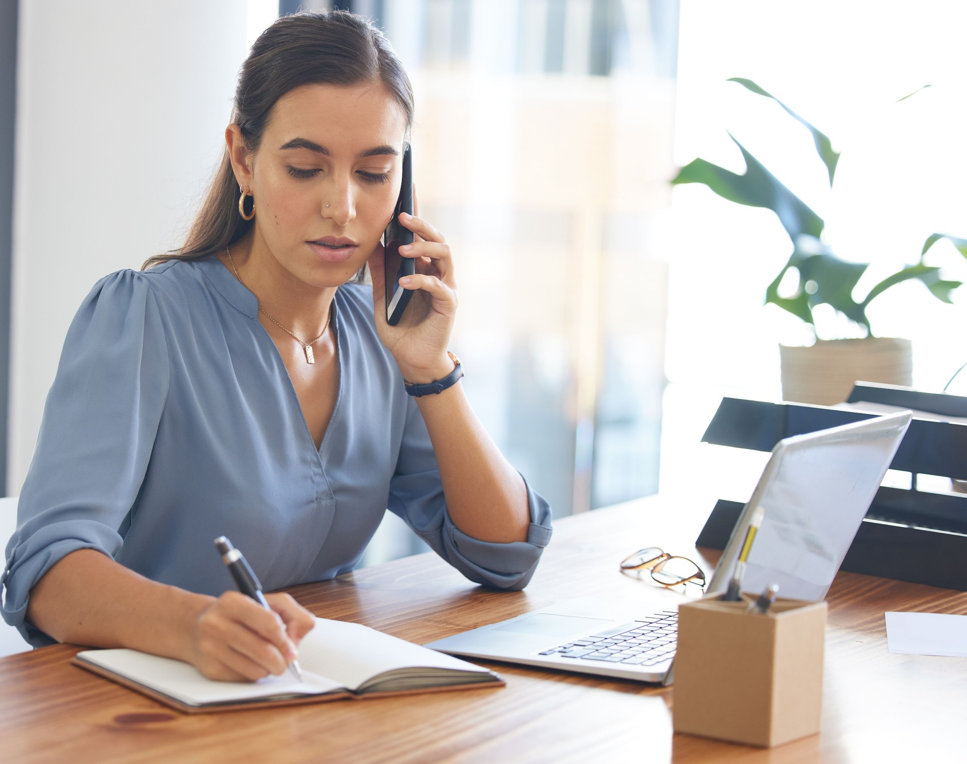 Business, woman writing and phone call in office, conversation or confirm schedule. Female employee, assistant or administrator make notes, cellphone for connection or planning for marketing calendar